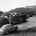 1950s Austin car driving up the Hollywood Hills with Hollywood sign in distance Los Angeles CA USA 